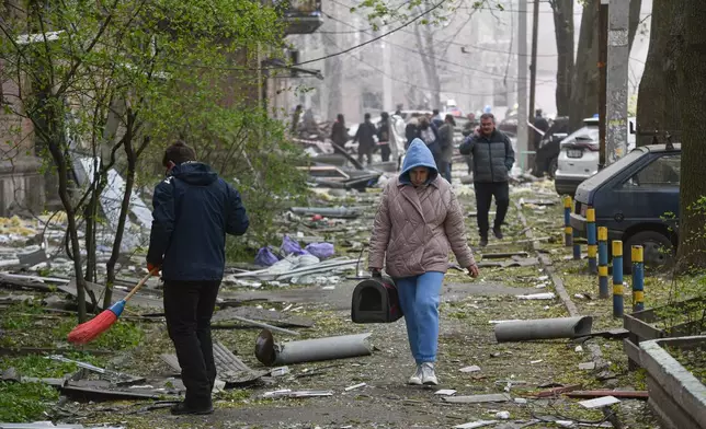 A woman walks in a yard of a residential building damaged by a Russian strike on Dnipro, Ukraine, Saturday, April 25, 2026. (AP Photo/Mykola Synelnykov)