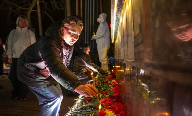 A man lights a candle at a memorial dedicated to firefighters and workers who died after the 1986 Chornobyl (Chernobyl) nuclear disaster, ahead of its 40th anniversary in Slavutych, Ukraine, Saturday, April 25, 2026. Chornobyl is the Ukrainian name for the city. (AP Photo/Dan Bashakov)
