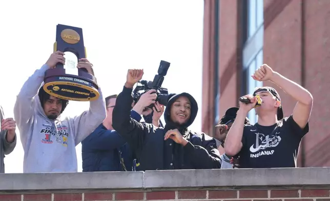 Michigan's Elliot Cadeau, left, Nimari Burnett, center, and Will Tschetter, right, celebrate as the team returns to campus Tuesday, April 7, 2026, in Ann Arbor, Mich., the day after defeating UConn at the Final Four of the NCAA college basketball tournament. (AP Photo/Paul Sancya)