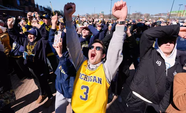 Michigan fans including Nick Weykamp celebrate winning the NCAA basketball tournament championship with the team as they return to campus Tuesday, April 7, 2026, in Ann Arbor, Mich. (AP Photo/Paul Sancya)