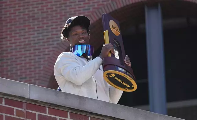 Michigan's L.J. Cason holds the National Championship trophy upon returning to campus Tuesday, April 7, 2026, in Ann Arbor, Mich., the day after defeating UConn at the Final Four of the NCAA college basketball tournament. (AP Photo/Paul Sancya)