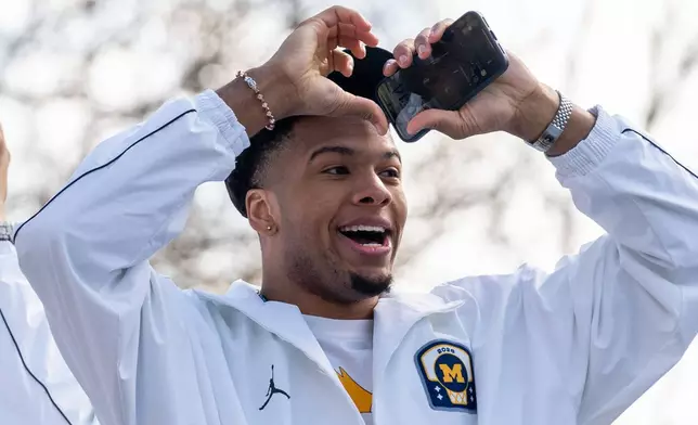 Michigan's Trey McKenney throws a heart sign to fans during a parade celebrating their national championship win in the NCAA college basketball tournament , Saturday, April 11, 2026, in Ann Arbor, Mich. (Devin Anderson-Torrez/Ann Arbor News via AP)