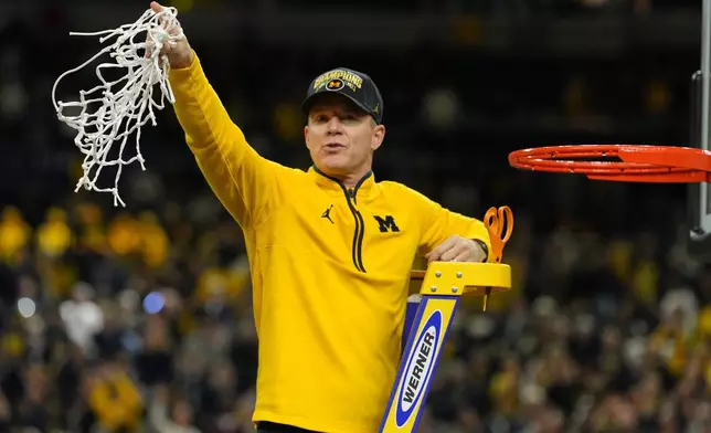 Michigan head coach Dusty May celebrates by cutting down the net after defeating UConn in the NCAA college basketball tournament national championship game at the Final Four, Monday, April 6, 2026, in Indianapolis. (AP Photo/Michael Conroy)