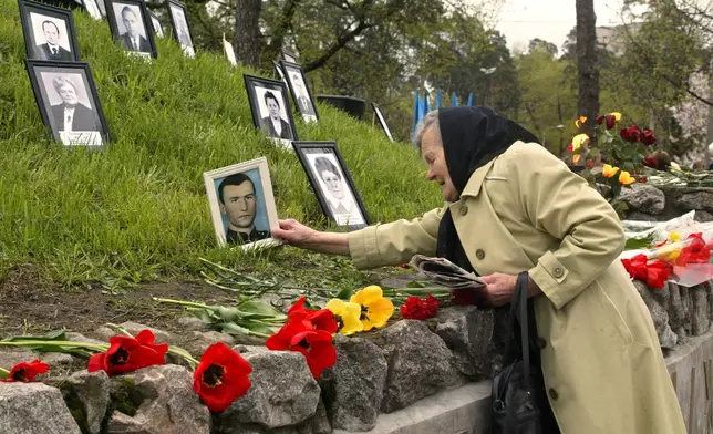 FILE - Praskoviya Nezhyvova places a photo of her son, Viktor, who died following cleanup operations from the 1986 Chernobyl nuclear plant accident, at a monument to the victims in Kyiv, April 26, 2004. (AP Photo/Efrem Lukatsky, File)
