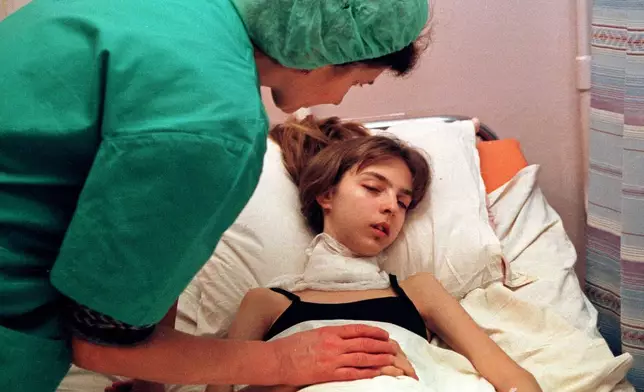 FILE - A medical worker attends to a 17-year-old girl recovering from surgery to remove her cancerous thyroid at the intensive therapy unit of the Endocrynology Institute in Kyiv, Ukraine, Nov. 30, 2000, nearly 15 years after the explosion and fire at the Chernobyl nuclear power plant. (AP Photo/Efrem Lukatsky, File)