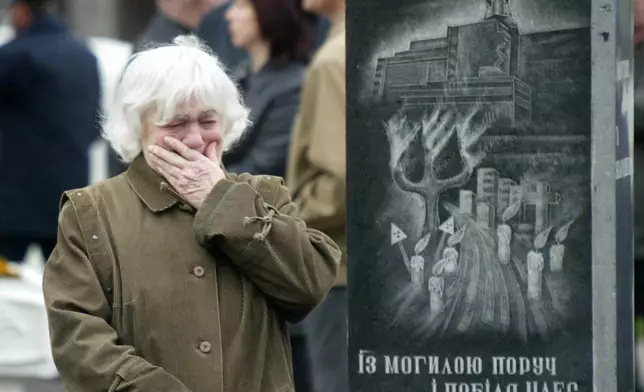 FILE - Alehandra Lihova, sister of a worker who died following cleanup operations from the 1986 explosion and fire at the Chernobyl nuclear power plant, wipes away tears at a wreath-laying ceremony at a monument to victims in Kyiv, Ukraine, April 26, 2004. The monument depicts the plant and its inscription reads "Near the grave, near the Chernobyl nuclear power station, near the dead Prypiat, a tree is the cross." (AP Photo/Efrem Lukatsky, File)