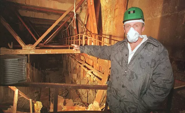 FILE - An investigator points toward damaged Reactor No. 4 inside the Chernobyl nuclear power plant in Chernobyl, Ukraine, Nov. 10, 2000. (AP Photo/Efrem Lukatsky, File)