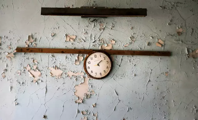 FILE - A broken clock hangs on a wall in a school in the deserted town of Pripyat, Ukraine, April 5, 2017, once home to people whose lives were connected to the Chernobyl nuclear power plant about 3 kilometers (nearly 2 miles) away. (AP Photo/Efrem Lukatsky, File)