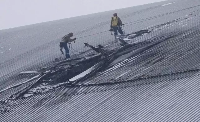 FILE - Workers examine the damage to the roof of the New Safe Confinement structure, which was built to contain the radioactive remains of Reactor No. 4 at the Chernobyl nuclear power plant, following what Ukrainian officials said was a Russian drone attack in Chernobyl, Ukraine, Feb. 14, 2025. (AP Photo/Efrem Lukatsky, File)