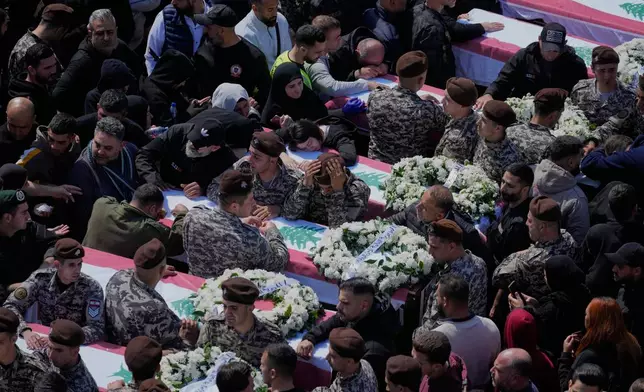 Colleagues mourn over the coffins during the funeral of 13 state security officers killed the previous day in an Israeli strike in the Lebanese coastal city of Sidon, Saturday, April 11, 2026. (AP Photo/Mohammed Zaatari)