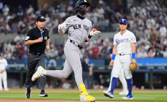 New York Yankees' Jazz Chisholm Jr. celebrates his solo home run in the fourth inning of a baseball game as umpire Ben May and Texas Rangers third baseman Josh Jung, right rear, look on Monday, April 27, 2026, in Arlington, Texas. (AP Photo/Tony Gutierrez)