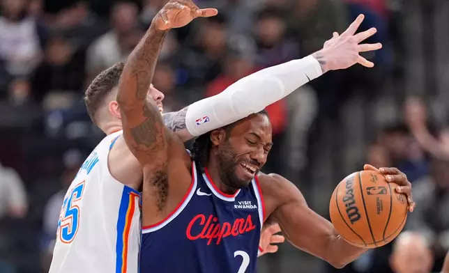 Oklahoma City Thunder center Isaiah Hartenstein, left, reaches over Los Angeles Clippers forward Kawhi Leonard during the first half of an NBA basketball game Wednesday, April 8, 2026, in Inglewood, Calif. (AP Photo/Mark J. Terrill)