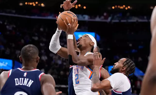 Oklahoma City Thunder guard Shai Gilgeous-Alexander, center, shoots as Los Angeles Clippers guard Kris Dunn, left, and forward Derrick Jones Jr., right, defend during the first half of an NBA basketball game Wednesday, April 8, 2026, in Inglewood, Calif. (AP Photo/Mark J. Terrill)