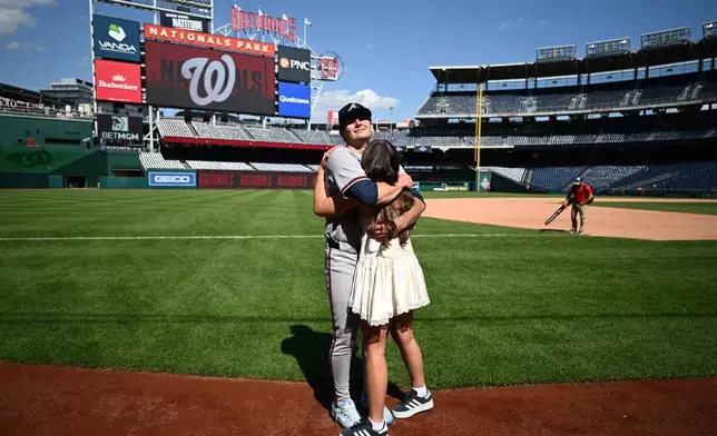 Atlanta Braves starting pitcher JR Ritchie, back, hugs his fiancée Makena Miller after winning his major league debut baseball game against the Washington Nationals, Thursday, April 23, 2026, in Washington. (AP Photo/Nick Wass)