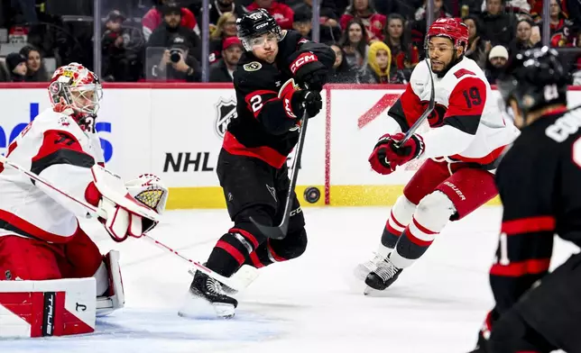 Ottawa Senators' Shane Pinto (12) tries pass to teammate Nick Cousins (21) in front of Carolina Hurricanes' goaltender Frederik Andersen (31) during the second period of an NHL hockey game in Ottawa, Ontario, on Sunday, April 5, 2026. (Spencer Colby/The Canadian Press via AP)