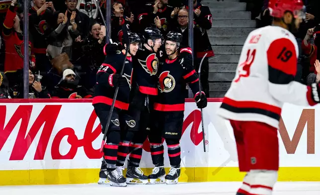 Ottawa Senators' Brady Tkachuk (7), centre, celebrates his goal on Carolina Hurricanes goaltender Frederik Andersen (31), not pictured, with teammate Ottawa Senators' Dylan Cozens (24), left, and Artem Zub (2) during the second period of an NHL hockey game, in Ottawa, Ontario, Sunday, April 5, 2026. (Spencer Colby/The Canadian Press via AP)