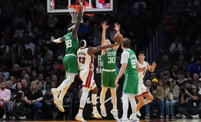 Boston Celtics forward Sam Hauser (30) blocks a shot by Miami Heat center Bam Adebayo (13) during the first half of an NBA basketball game, Wednesday, April 1, 2026, in Miami. (AP Photo/Lynne Sladky)