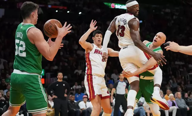 Boston Celtics guard Jordan Walsh, right, passes the ball to center Luka Garza (52) past Miami Heat center Bam Adebayo (13) during the first half of an NBA basketball game, Wednesday, April 1, 2026, in Miami. (AP Photo/Lynne Sladky)