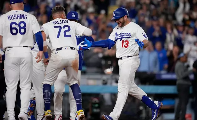 Los Angeles Dodgers' Max Muncy, right, scores after hitting a walk off solo home run during the ninth inning of a baseball game against the Texas Rangers, Friday, April 10, 2026, in Los Angeles. (AP Photo/Mark J. Terrill)