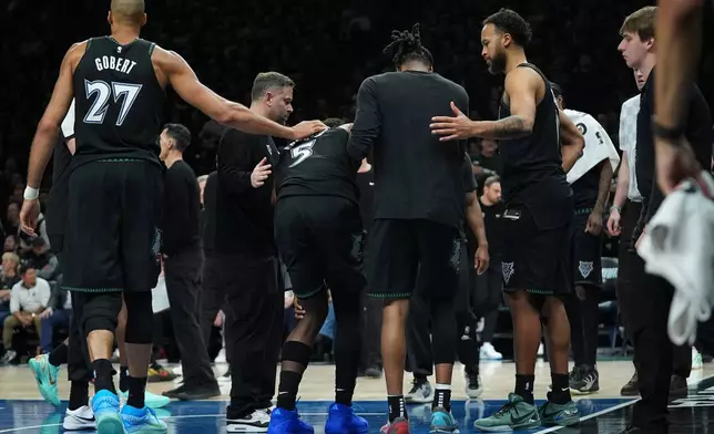 Minnesota Timberwolves guard Anthony Edwards (5) is helped off the court after sustaining an injury during the first half of Game 4 of a first-round NBA basketball playoff series against the Denver Nuggets, Saturday, April 25, 2026, in Minneapolis. (AP Photo/Abbie Parr)