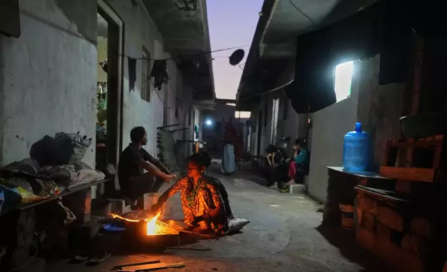 A migrant woman prepares a meal using firewood at a deserted ceramics workers' quarters in Morbi, in the Indian state of Gujarat, Wednesday, April 8, 2026. (AP Photo/Ajit Solanki)
