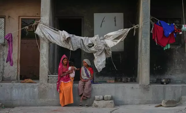 A migrant worker family sits in a deserted ceramics housing in Morbi, in the Indian state of Gujarat, Wednesday, April 8, 2026. (AP Photo/Ajit Solanki)