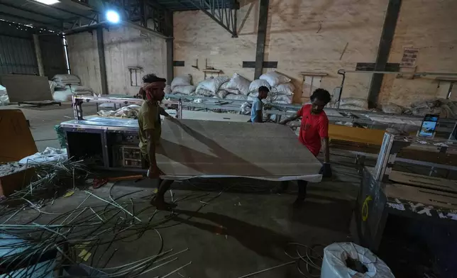 Migrant workers carry ceramic tiles at a factory in Morbi, in the Indian state of Gujarat, Wednesday, April 8, 2026. (AP Photo/Ajit Solanki)
