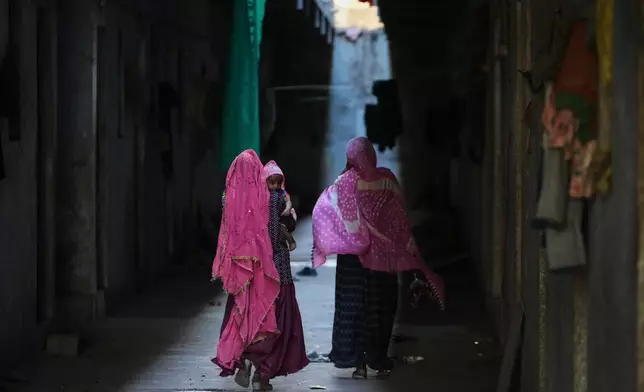 A family of migrant workers returns to their quarters in Morbi, in the Indian state of Gujarat, Wednesday, April 8, 2026. (AP Photo/Ajit Solanki)