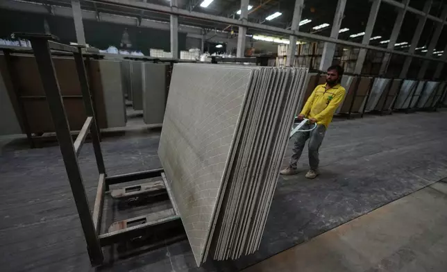 A migrant worker stacks ceramic tiles in a factory in Morbi, in the Indian state of Gujarat, Wednesday, April 8, 2026. (AP Photo/Ajit Solanki)