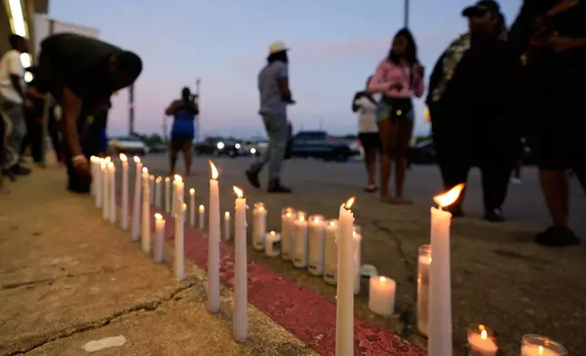 A man lights a candle during a prayer vigil for the victims of a mass shooting earlier in the day, Sunday, April 19, 2026, in Shreveport, La. (AP Photo/Gerald Herbert)