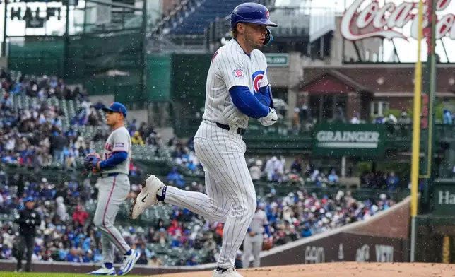 Chicago Cubs' Nico Hoerner, foreground, walks to first during the first inning of a baseball game against the New York Mets in Chicago, Sunday, April 19, 2026. (AP Photo/Nam Y. Huh)