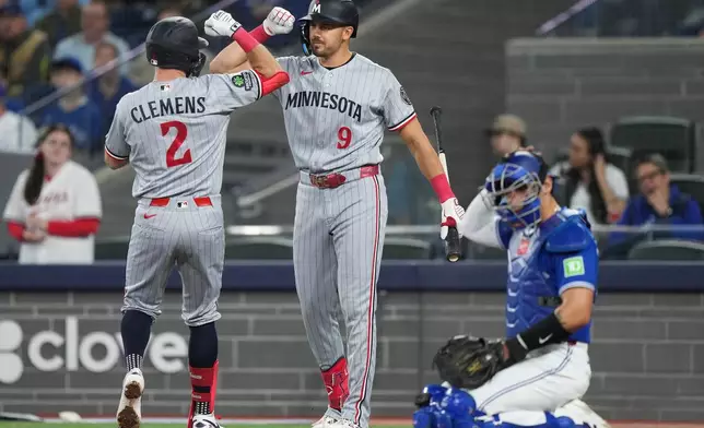 Minnesota Twins' Kody Clemens (2) celebrates with teammate Trevor Larnach (9) after hitting a solo home run during third-inning baseball game action against the Toronto Blue Jays in Toronto, Sunday, April 12, 2026. (Nathan Denette/The Canadian Press via AP)