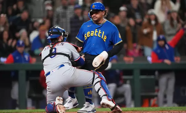 Seattle Mariners' Josh Naylor is tagged out at home by Texas Rangers catcher Danny Jansen trying to score on a single from Mariners' J.P. Crawford during the sixth inning of a baseball game, Friday, April 17, 2026, in Seattle. (AP Photo/Lindsey Wasson)