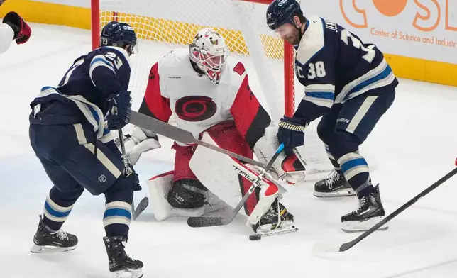 Carolina Hurricanes goaltender Brandon Bussi (32) kicks the puck away from Columbus Blue Jackets center Sean Monahan (23) and center Boone Jenner (38) in the first period of an NHL game in Columbus, Tuesday, March 31, 2026. (AP Photo/Sue Ogrocki)