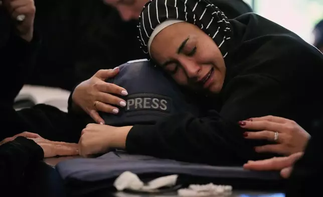 Zainab, the sister of Lebanese journalist Amal Khalil, who was killed on Wednesday in an Israeli airstrike, hugs her helmet as she mourns over her coffin in the village of Baysariyeh, southern Lebanon, Thursday, April 23, 2026. (AP Photo/Mohammed Zaatari)