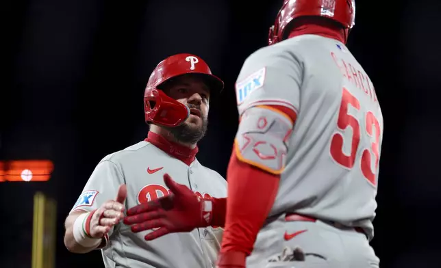 Philadelphia Phillies' Kyle Schwarber, left, is congratulated by Adolis García (53) after scoring on a double hit by Alec Bohm during the seventh inning of a baseball game against the San Francisco Giants in San Francisco, Monday, April 6, 2026. (AP Photo/Jed Jacobsohn)