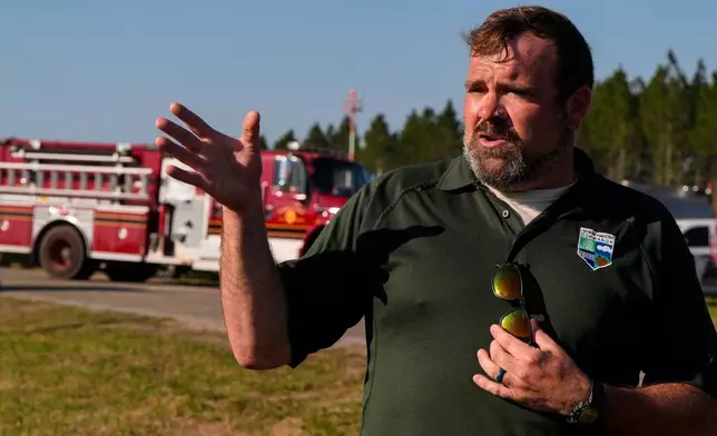 Seth Hawkins with the Georgia Forestry commision speaks to the media as fire crews and truck assemble at the Brantley County Airport as they work the Brantley highway 82 fire, Thursday, April 23, 2026, near Nahunta, Ga. (AP Photo/Mike Stewart)