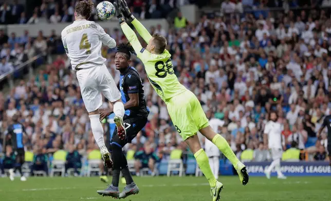 FILE - From left, Real Madrid's Sergio Ramos, Brugge's Simon Deli and Brugge's goalkeeper Simon Mignolet go for the ball during the Champions League group A soccer match between Real Madrid and Club Brugge, at the Santiago Bernabeu stadium in Madrid, Oct.1, 2019. (AP Photo/Manu Fernandez, File)