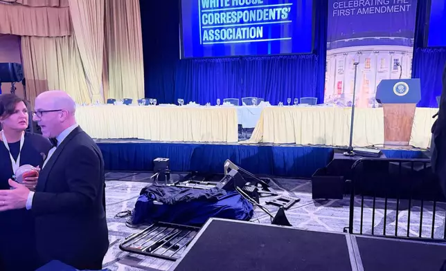 The empty stage is seen after President Donald Trump and other top leaders were evacuated from an annual dinner of White House correspondents on Saturday night, April 25, 2026, in Washington. (AP Photo/Zeke Miller)