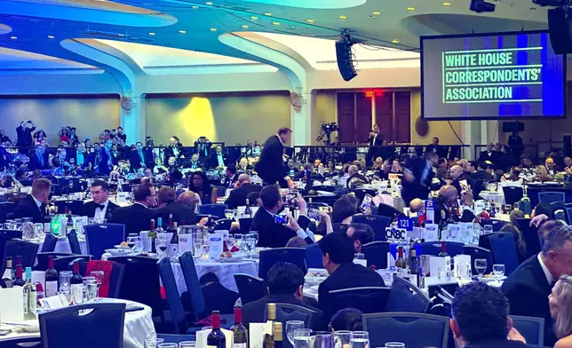 Guests take cover under tables after a shooting incident outside the ballroom during the White House Correspondents Dinner, Saturday, April 25, 2026, in Washington. (AP Photo/Alex Brandon)