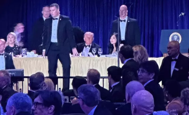 U.S. Secret Service agents surround President Donald Trump after a shooting incident outside the ballroom during the White House Correspondents Dinner, Saturday, April 25, 2026, in Washington. (AP Photo/Alex Brandon)