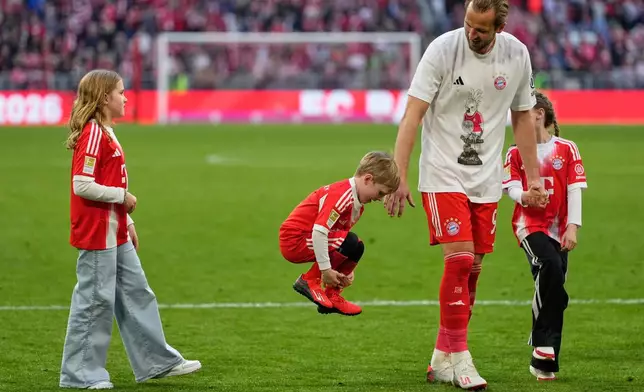 Bayern's Harry Kane walks with his children after his team clinched the German league title after a Bundesliga soccer match between Bayern and Stuttgart in Munich, Germany, Sunday, April 19, 2026. (AP Photo/Matthias Schrader)