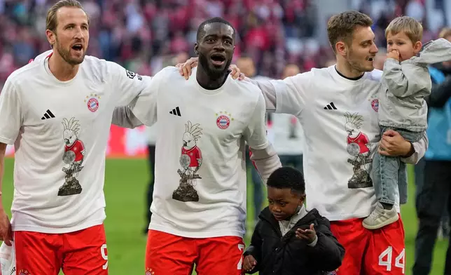 FILE - Bayern's Harry Kane, left, Dayot Upamecano, center, and Josip Stanisic celebrate with their kifds celebrate after their team clinched the German league title after during a Bundesliga soccer match between Bayern and Stuttgart in Munich, Germany, April 19, 2026. (AP Photo/Matthias Schrader, File)