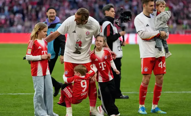 Bayern's Harry Kane hugs his kids after his team clinched the German league title after a Bundesliga soccer match between Bayern and Stuttgart in Munich, Germany, Sunday, April 19, 2026. (AP Photo/Matthias Schrader)