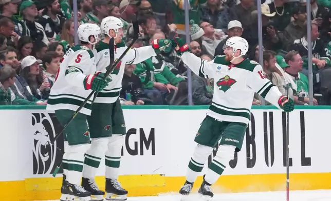 Minnesota Wild players, from left, Jake Middleton, Michael McCarron and Yakov Trenin react to a goal by McCarron during the third period in Game 5 of a first-round NHL Stanley Cup playoffs hockey series against the Dallas Stars, Tuesday, April 28, 2026, in Dallas. (AP Photo/Julio Cortez)