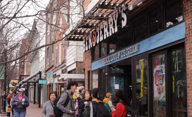 People eat ice cream outside the Ben and Jerry's scoop shop on Free Cone Day on Free Cone Day in Burlington, Vt., Tuesday, April 14, 2026. (AP Photo/Amanda Swinhart)