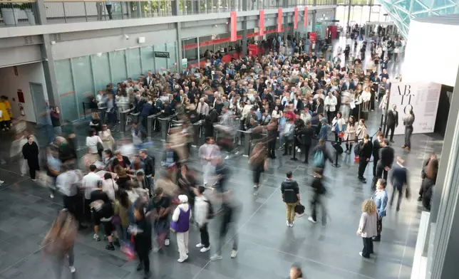 Business operators and visitors enter the grounds of the Milan Design Week fair in Rho, Italy, Tuesday, April 21, 2026. (AP Photo/Luca Bruno)