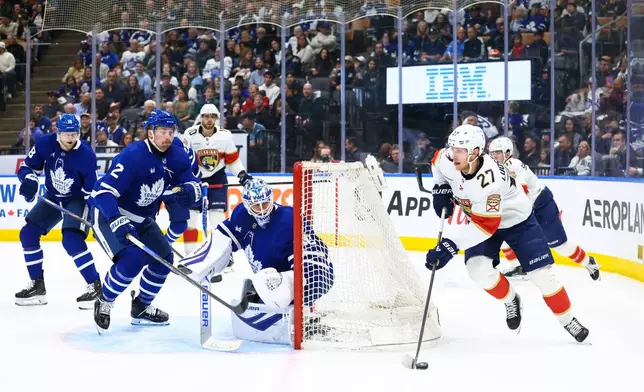 Florida Panthers' Eetu Luostarinen (27) takes the puck around the net as Toronto Maple Leafs' Simon Benoit (2) and goaltender Joseph Woll, center, defend in front of the net during first-period NHL hockey game action in Toronto, Saturday, April 11, 2026. (Cole Burston/The Canadian Press via AP)