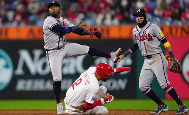 Atlanta Braves' Ozzie Albies, top left, attempts a double play after a force out of Philadelphia Phillies' Justin Crawford, bottom left, during the fifth inning of a baseball game, Sunday, April 19, 2026, in Philadelphia. (AP Photo/Derik Hamilton)