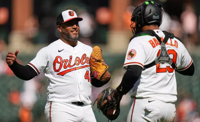 Baltimore Orioles pitcher Albert Suarez, left, and catcher Samuel Basallo, right, celebrate their team's victory over the Texas Rangers after a pitch call was overturned through the Automated Ball-Strike system in the ninth inning of a baseball game, Wednesday, April 1, 2026, in Baltimore. (AP Photo/Stephanie Scarbrough)